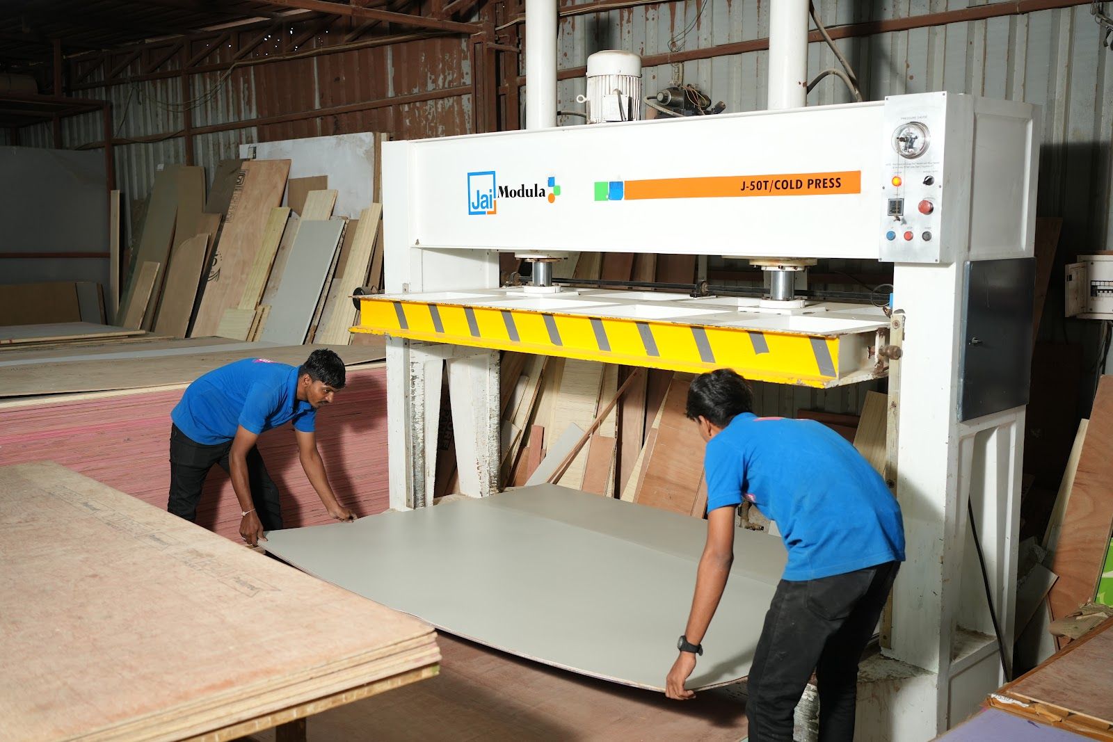 Workers loading a panel into the hot press at the AS9 factory