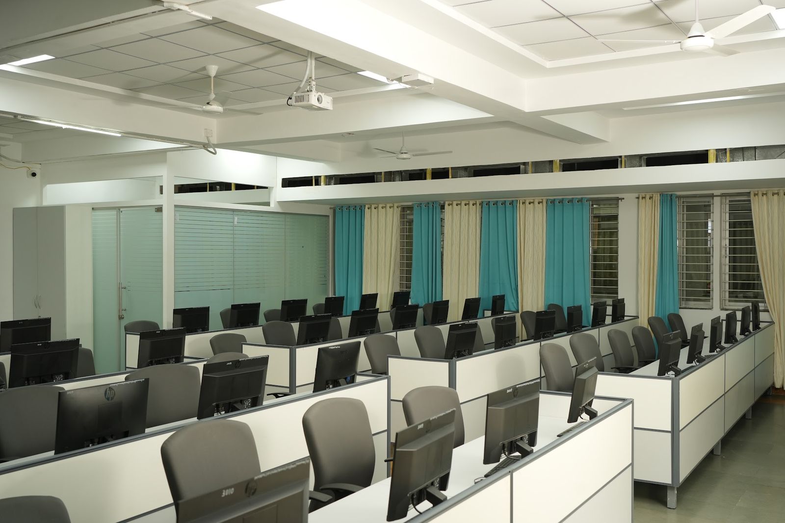 Computer lab with partitioned workstations beside a glass cabin