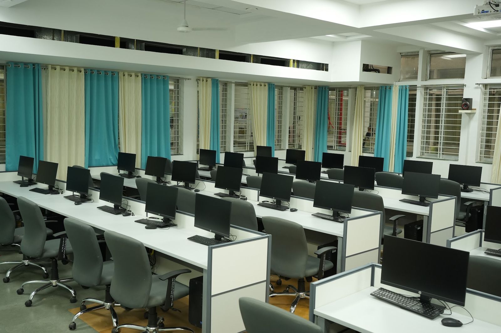 Computer lab with rows of white workstations and grey ergonomic chairs, made by AS9 Interiors