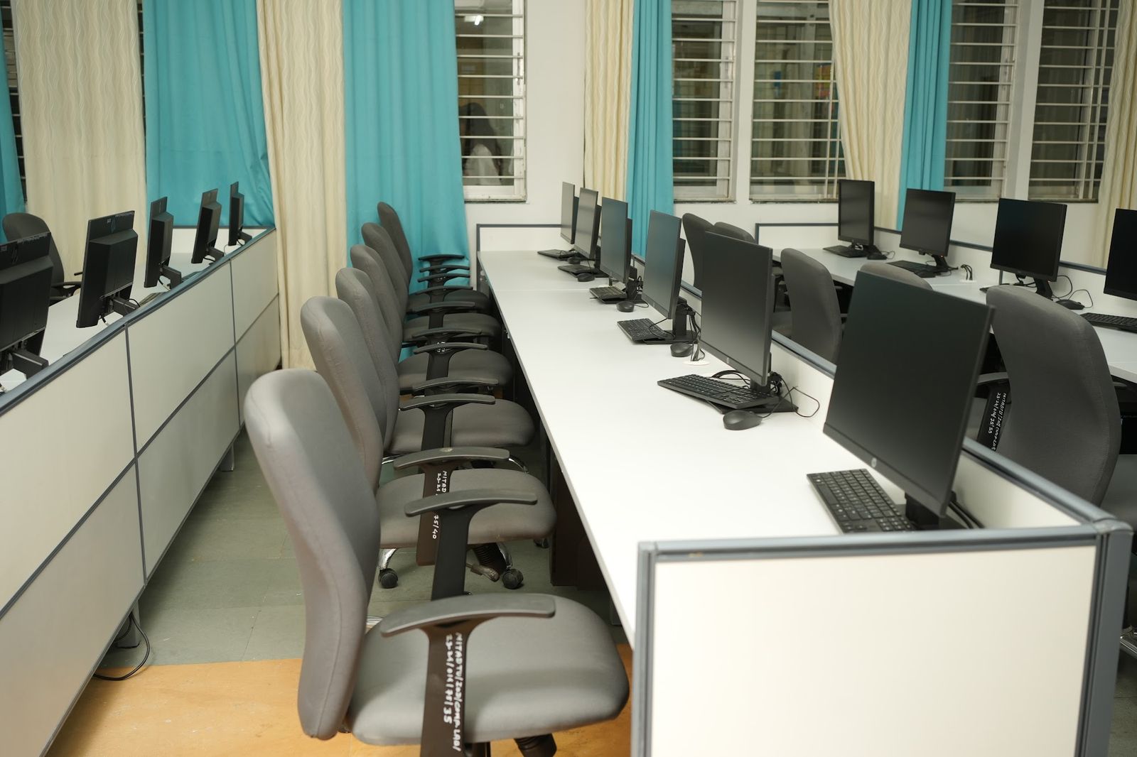 Row of workstations with ergonomic chairs and side partitions