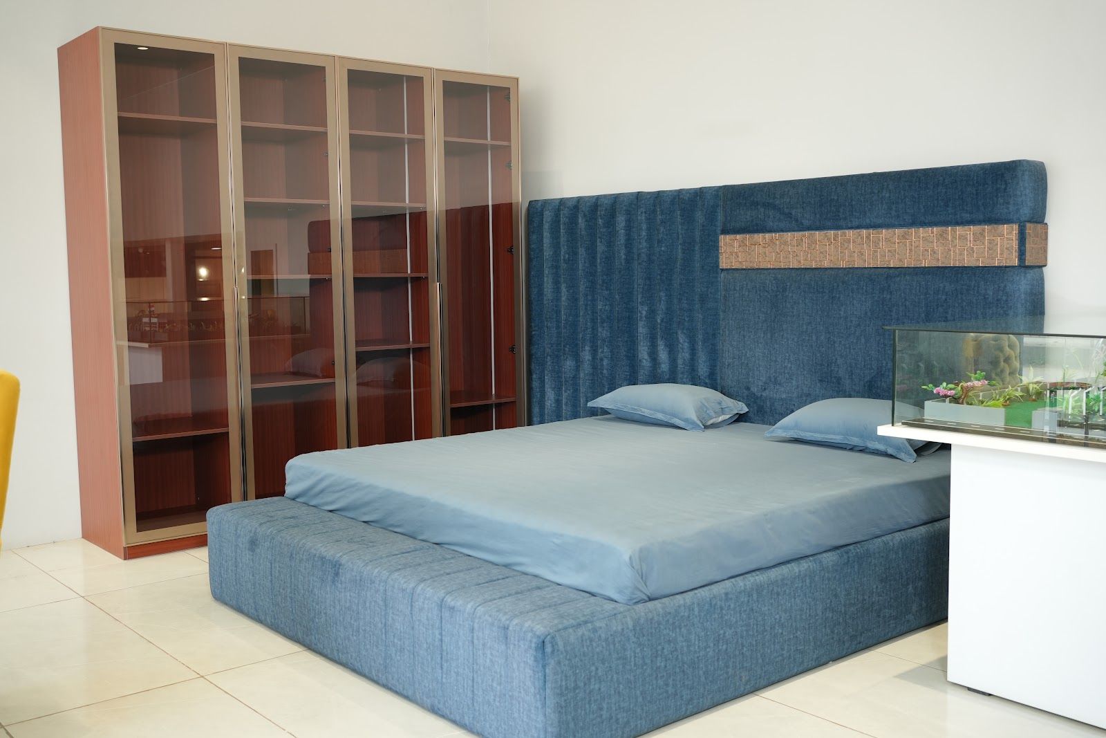 Blue upholstered bed with a walnut glass-front wardrobe in the AS9 showroom
