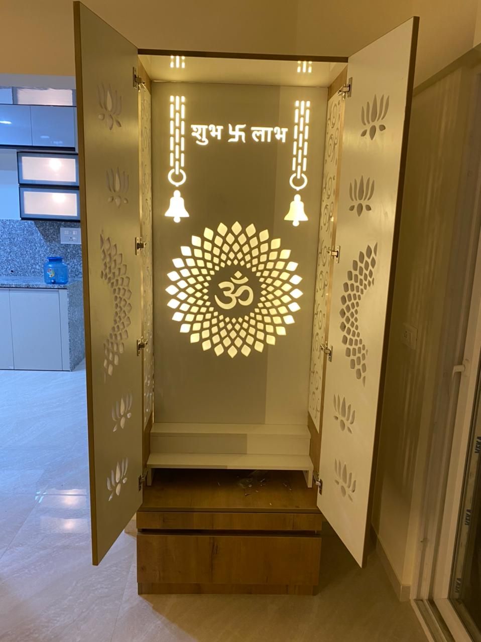 Backlit pooja unit with a carved Om jali panel and storage
