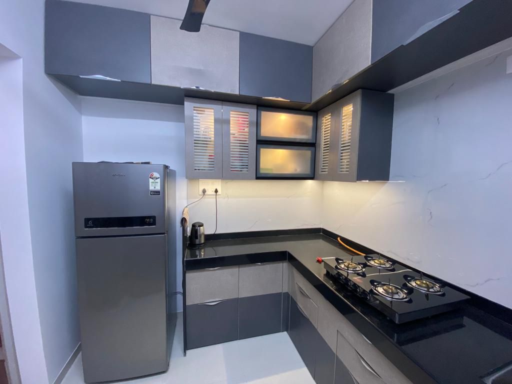 L-shaped modular kitchen in grey and white with glass-front wall cabinets