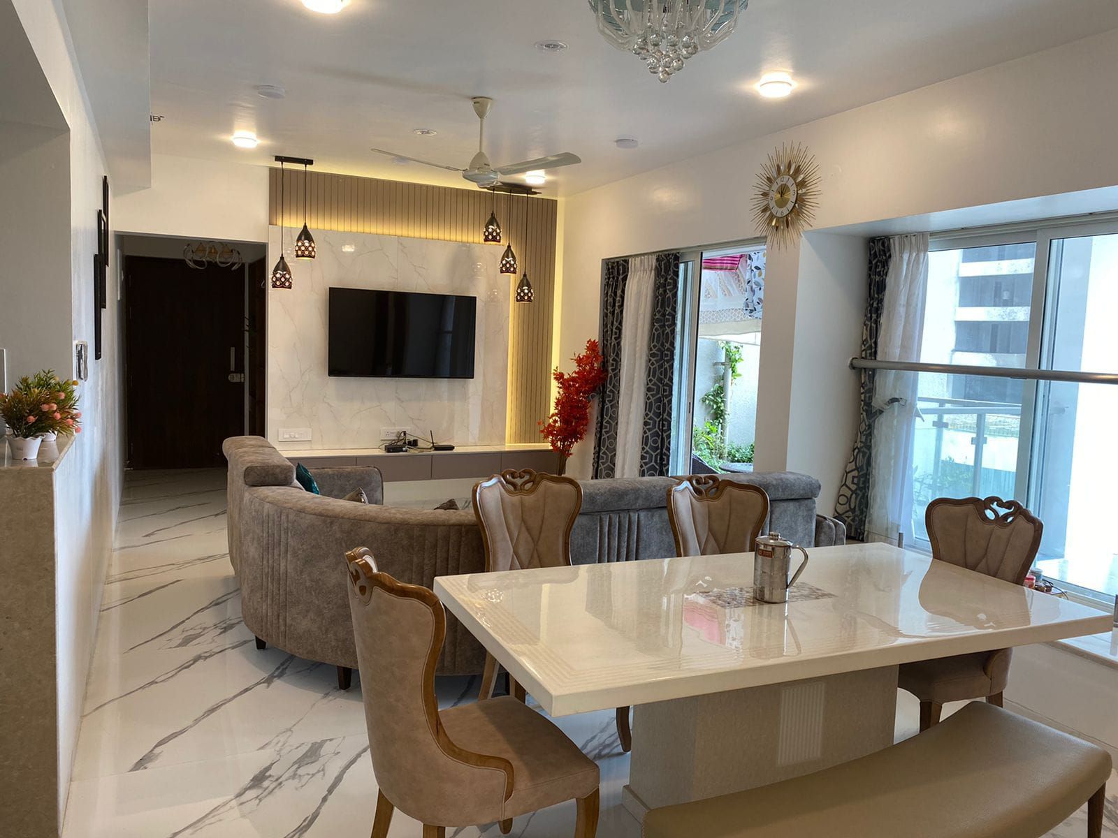 Open living and dining room with a marble-look TV wall, dining table and lounge seating