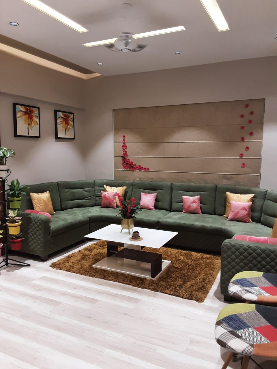 Living room with a green sectional sofa and patterned false ceiling