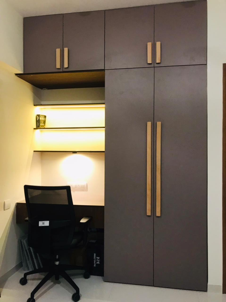 Floor-to-ceiling wardrobe with a built-in study table and lit open shelves